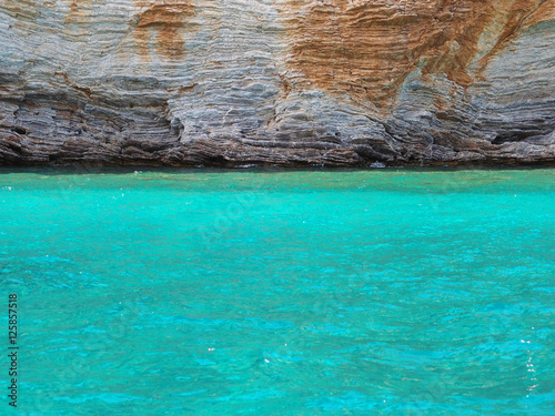 Contrast: turquoise sea and beige layered cliffs