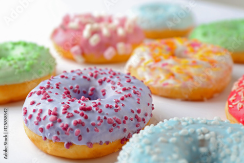 Tasty donuts with colorful sprinkles on light background