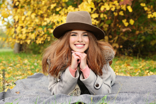 Beautiful young woman lying on blanket in a autumn park © Africa Studio