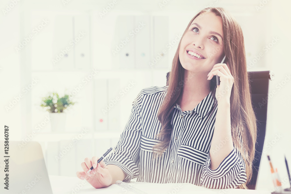 Cheerful secretary in striped shirt is talking on phone Cheerful secretary in striped shirt is talking on phone