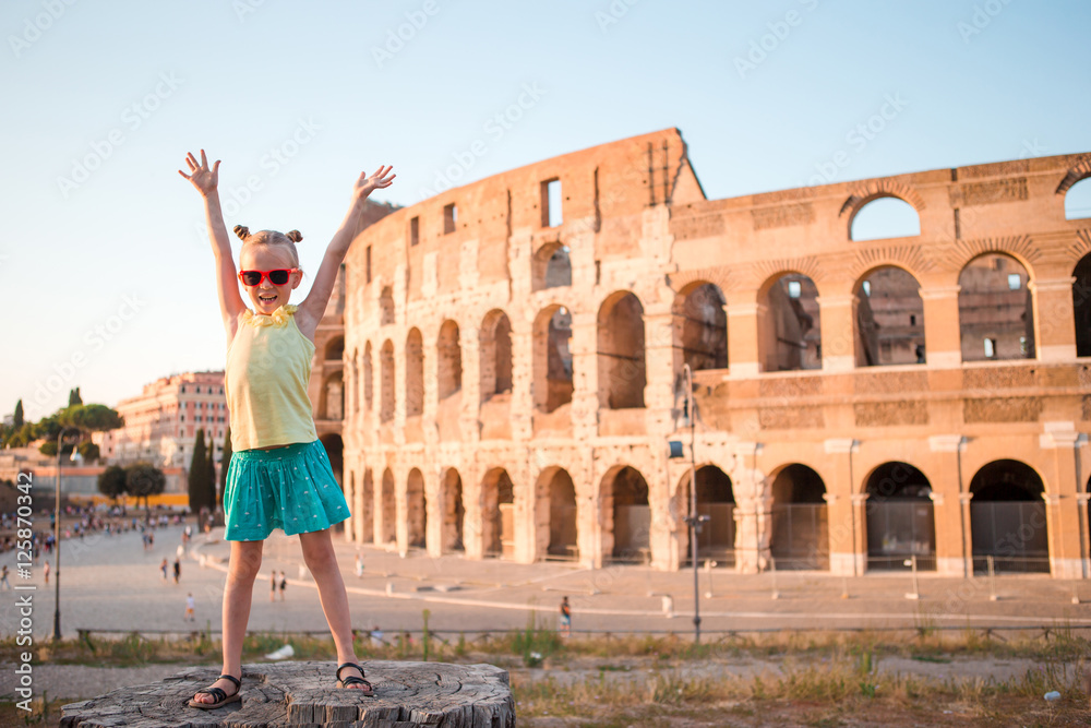 Adorable little active girl having fun in front of Colosseum in Rome, Italy.