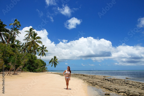 Young woman in bikini standing on the beach of Makaha'a island n photo