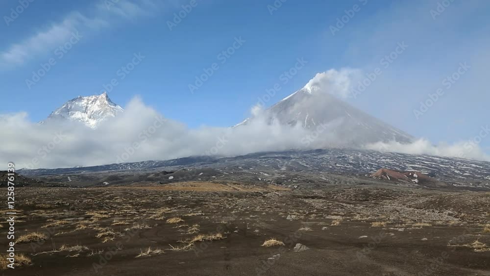 Beautiful Kamchatka volcanic landscape: view of Kamen Volcano and erupting Klyuchevskoy Volcano (Klyuchevskaya Sopka) on a sunny, and clear weather. Russian Far East, Klyuchevskaya Group of Volcanoes. Beautiful Kamchatka volcanic landscape: view of Kamen Volcano and erupting Klyuchevskoy Volcano (Klyuchevskaya Sopka) on a sunny, and clear weather. Russian Far East, Klyuchevskaya Group of Volcanoes.