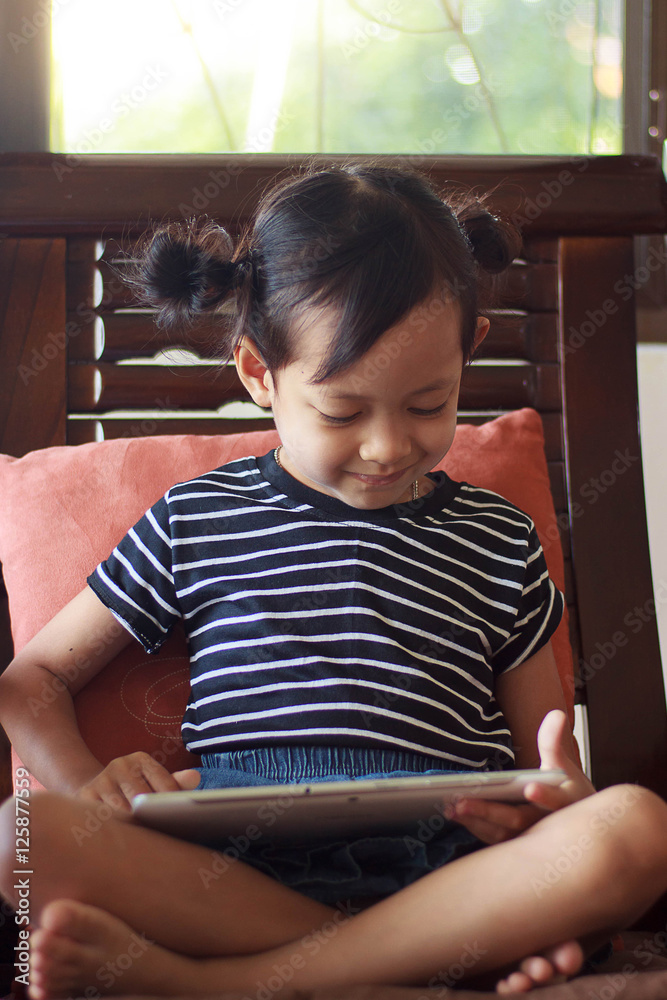 Happy child playing tablet or small computer at home with smile face. Happy child playing tablet or small computer at home with smile face.