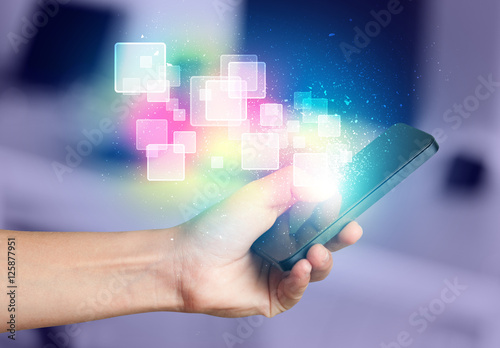 Hand holding smart phone with abstract glowing squares