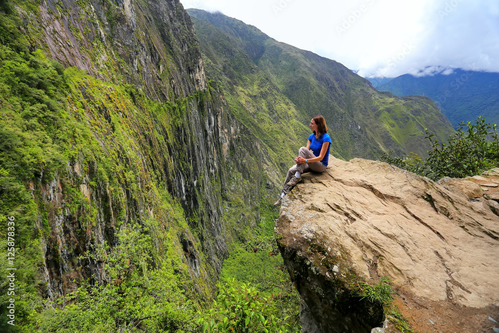 Young woman enjoying the view of Inca Bridge and cliff path near