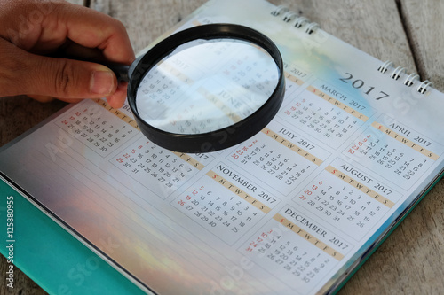Businessman study report using a magnifying glass. in calendar.