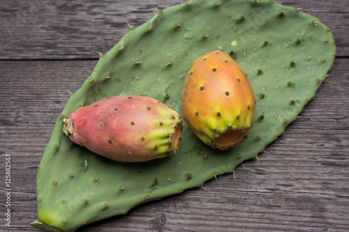 Fresh ripe whole prickly pears a leaf of the plant on wooden vin