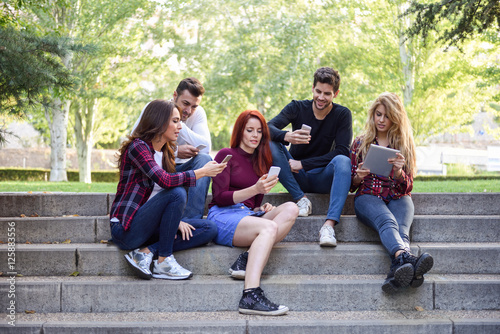 Young people using smartphone and tablet computers outdoors
