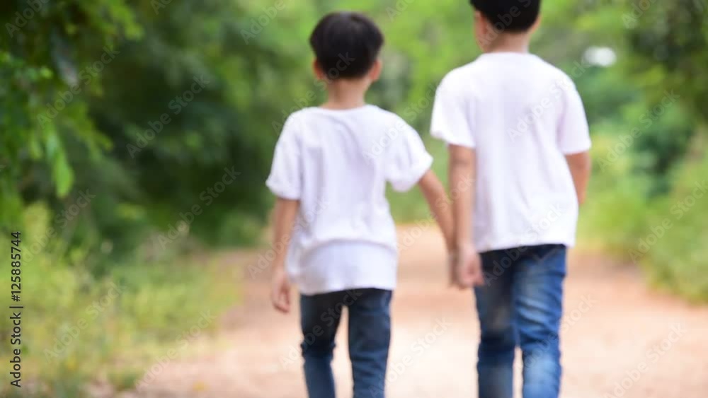 Two young Thai boy run together on the crack road in the natural park. Two young Thai boy run together on the crack road in the natural park.