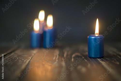 Lit four blue candles on wooden counter photo