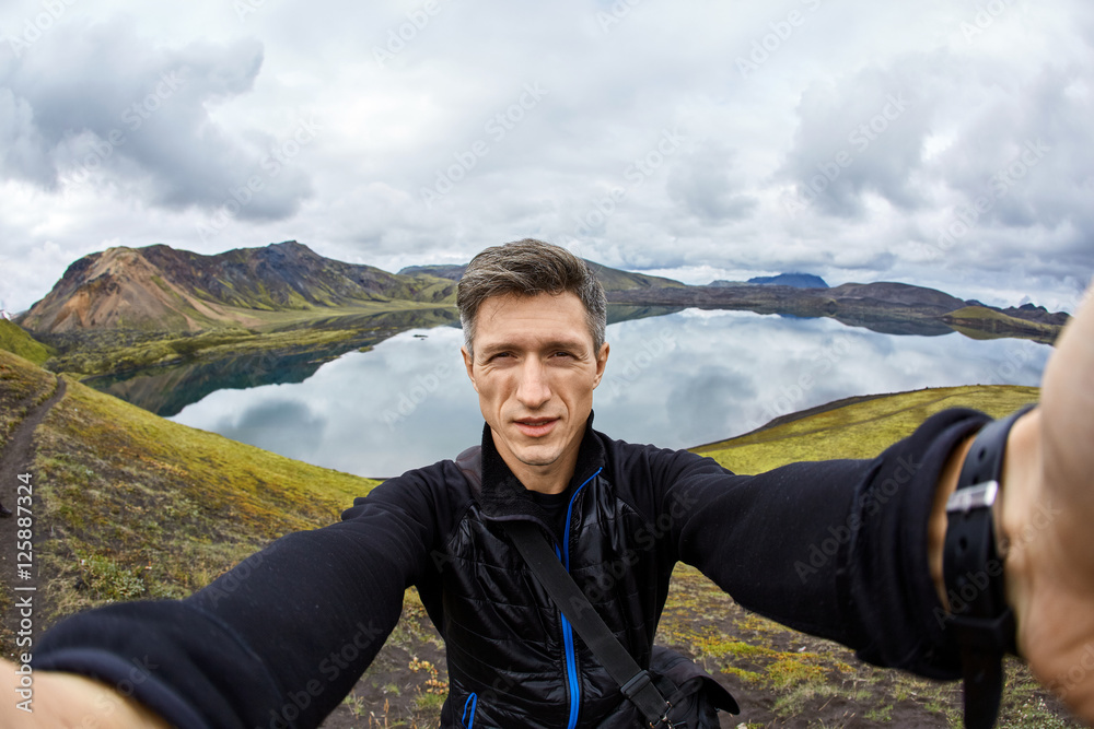 man hiker photographer taking selfie on the lake background in Iceland