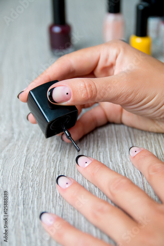 Black nail polish being applied to hand with tools for manicure on background. Beautiful  process. Close up. photo