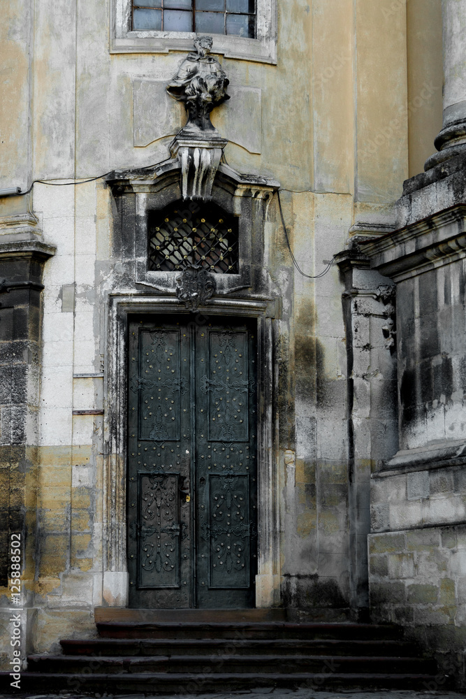 Facade of the Dominican Cathedral, Lviv, Ukraine. Fragment   with door and window  metal grill.