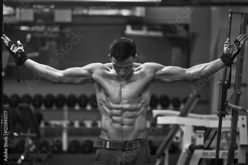 Athlete muscular brutal bodybuilder posing in the gym