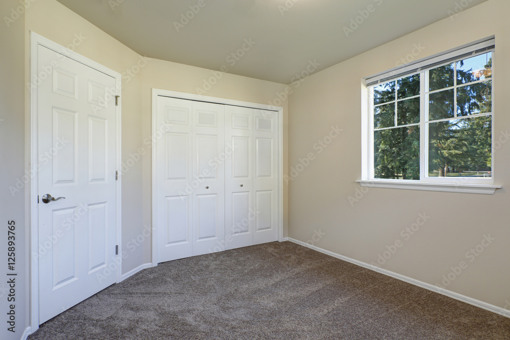 Fototapeta premium White doors closet and a window in empty beige room