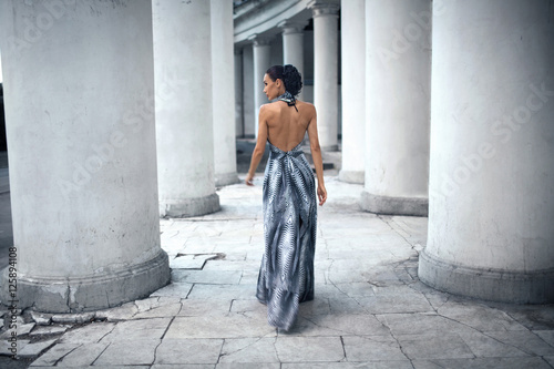 Bild auf Leinwand young lady in dress at the entrance of neoclassical building