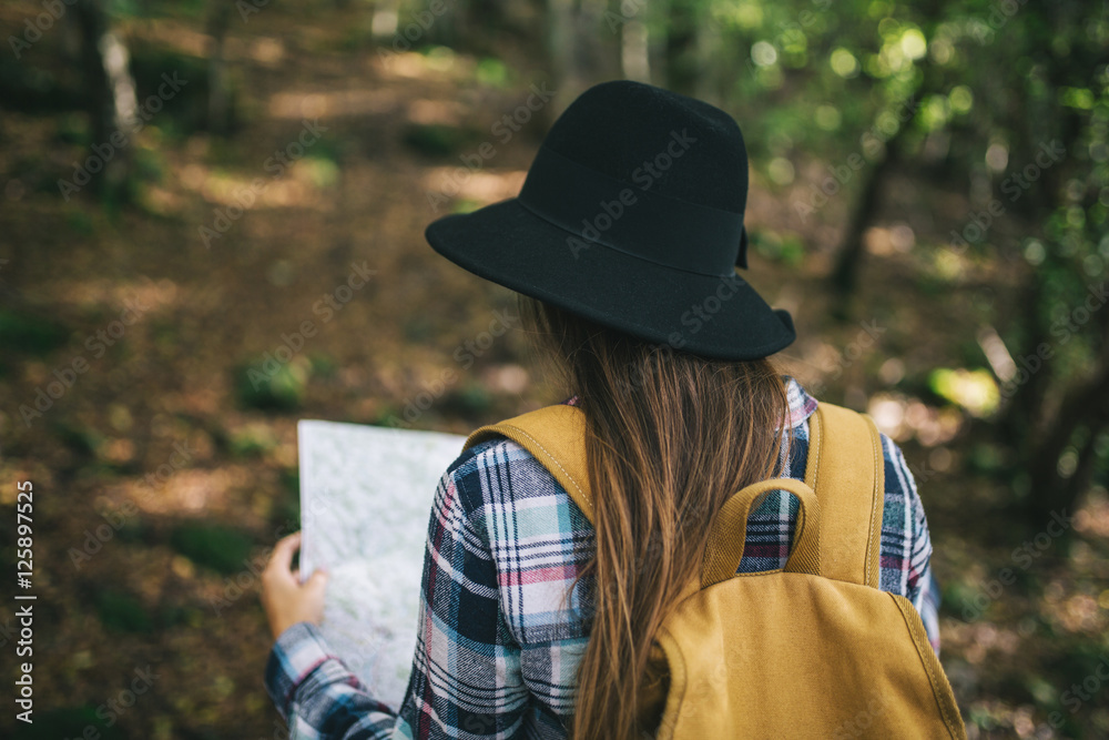 Yong woman lost in forest looking at map