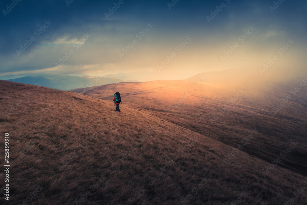 Lonely hiker  with backpack walking along the trail on the mountain top at foggy day time. Travel lifestyle concept.