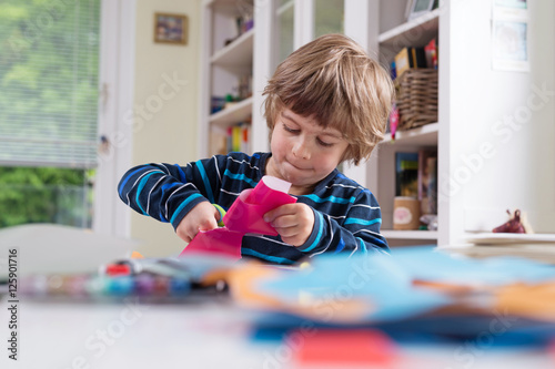 Fotografía Cute litle boy cutting shapes out of colored paper