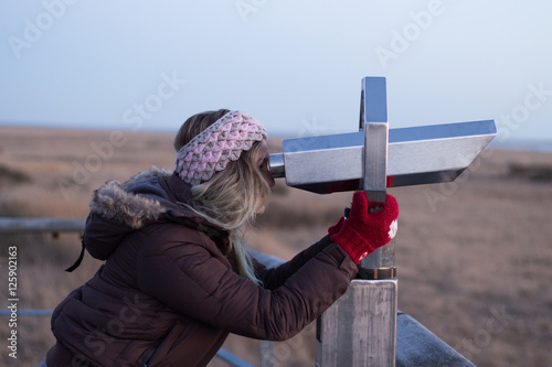 Frau guckt durch Fernrohr an der See