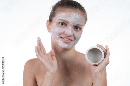 Two cosmetic mask of gray clay with scrub and cream on the face
