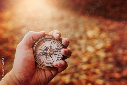 Hand holding a compass on natural blurry background photo