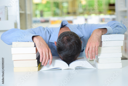 Man with head slumped in a book photo