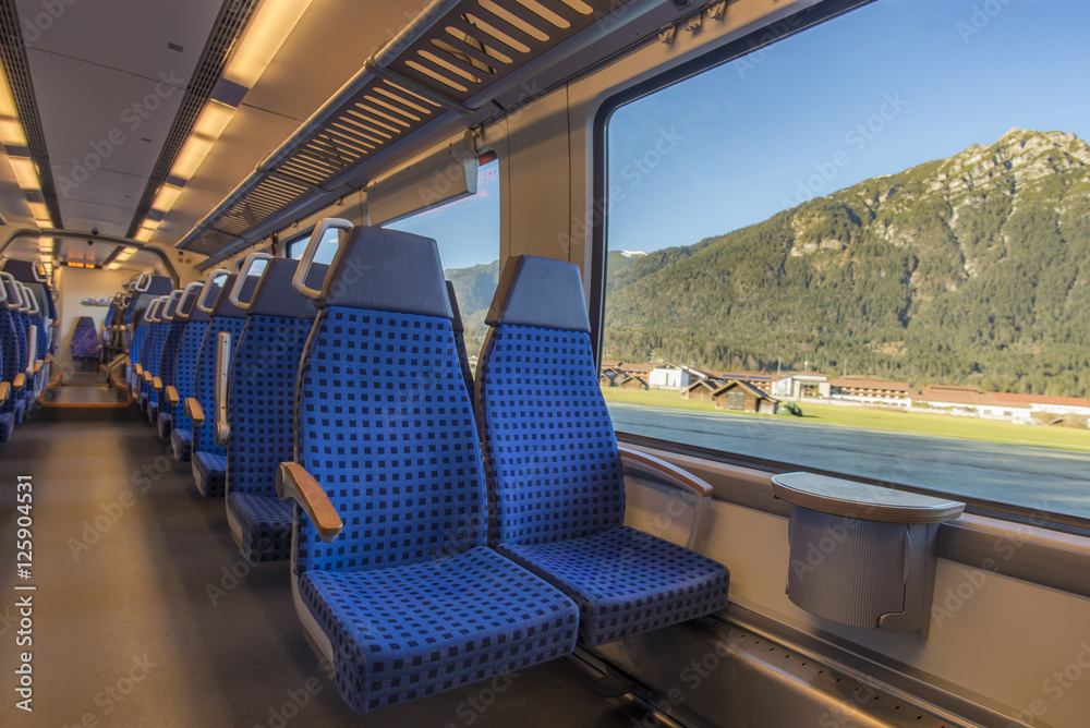 Fototapeta premium Krzesła i widok przez okno - Wygodne krzesła w nowoczesnym niemieckim pociągu, z pięknym widokiem na alpejskie okna