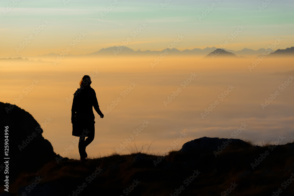 Silhouette of a hiker in the mountains with the sea of fog in th