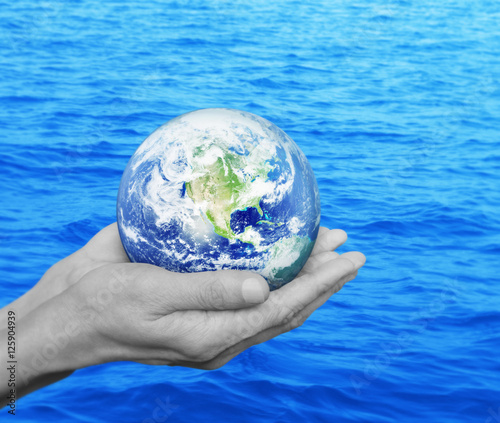 Earth in black and white hands over blue sea background, Environ