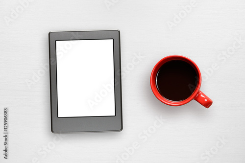 Electronic book and coffee cup on white table