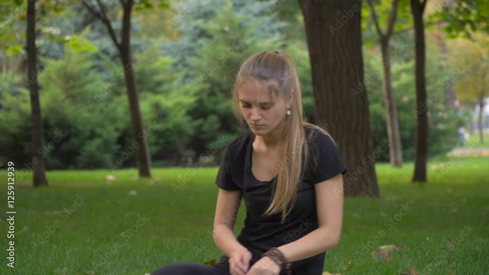 Young girl practicing yoga in the park on the green grass. Early autumn. In the grass are yellow leaves. The girl is young and healthy. Young girl practicing yoga in the park on the green grass. Early autumn. In the grass are yellow leaves. The girl is young and healthy.