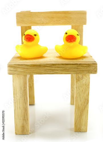 Ducks on a small wooden chair with a white background