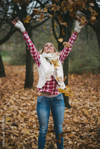 Portrait of a happy woman playing with autumn leaves outdoor