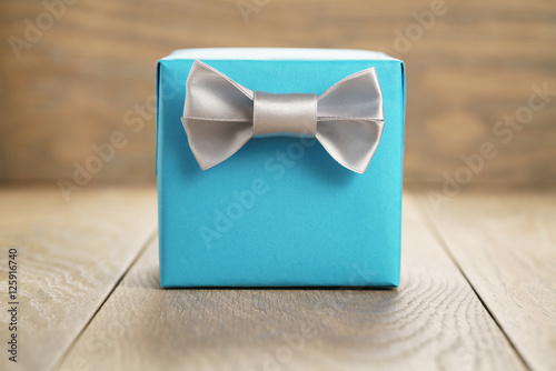 light blue gift box with minimalistic silver ribbon bow on wooden