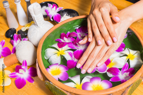 Woman hands with a bowl of aroma spa water on wooden table
