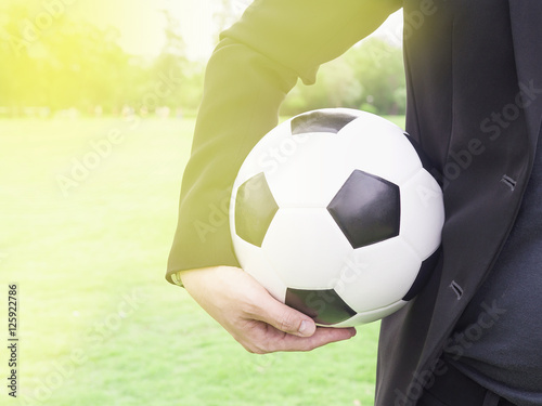 Soccer team manager is holding ball and green grass field background © pairhandmade