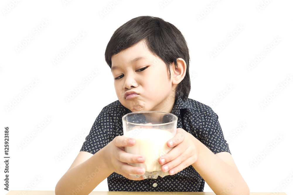 Asian boy is showing dislike drinking milk expression over white background Asian boy is showing dislike drinking milk expression over white background