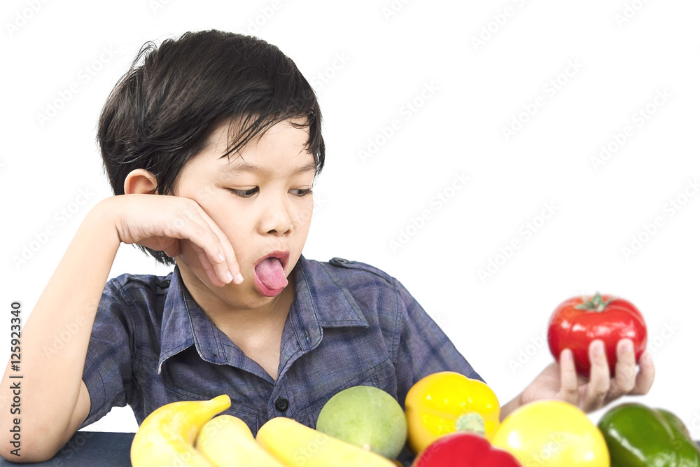 Asian boy is showing dislike vegetable expression over white background Asian boy is showing dislike vegetable expression over white background