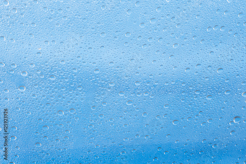 Rain drop on at glass window over blue sky background