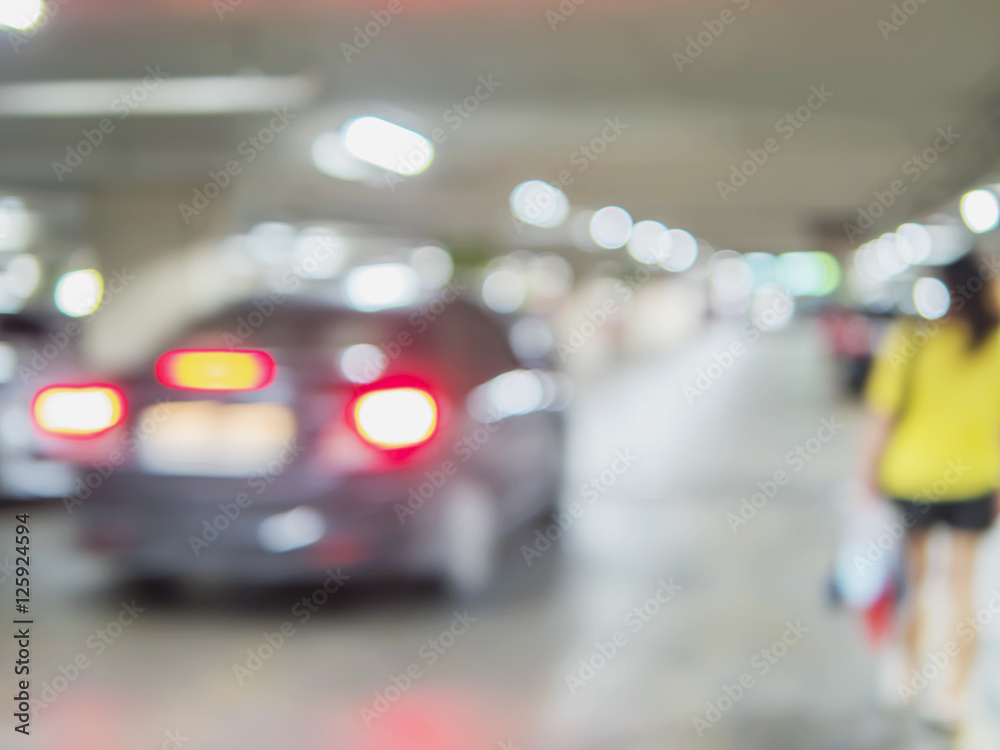 Fototapeta premium Niewyraźne zdjęcie kobiety idzie niebezpiecznie na parkingu samochodowym