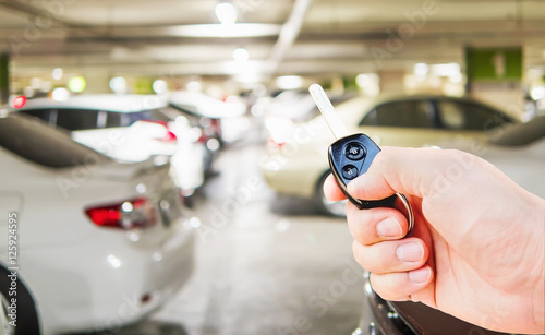 A man hand is pressing car remote key to open / close his car in the parking area © pairhandmade
