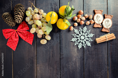 Black Christmas Background with empty copy space. Grapes, tangerine and nuts as a decorative xmas frame for xmas concept or cards photo