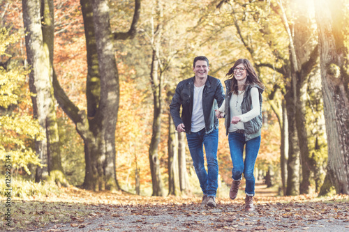 Junges Paar l  uft freudestrahlend durch den Herbstwald