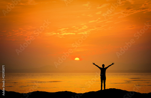 Landscapes image of Dramatic sunset over the sea with silhouette happy man on mountains