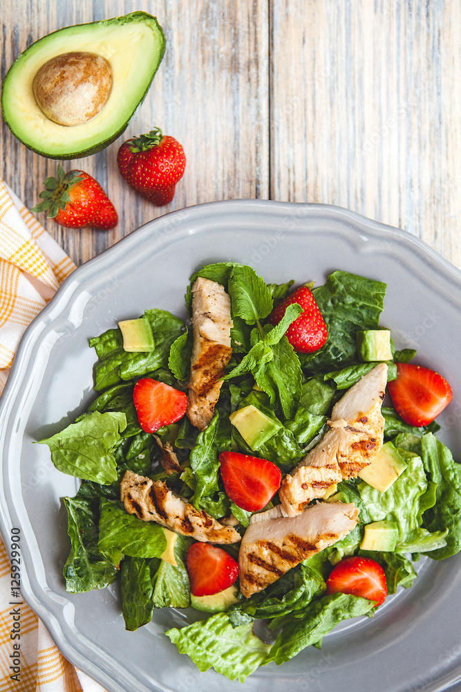 fresh salad with greens, avocado and strawberry, top view