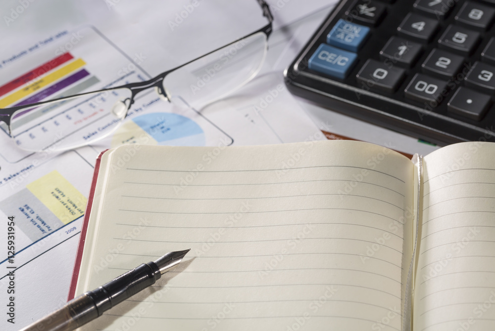 Business concept. Notebook with fountain pen, calculator, glasses on reports and paper with figures. Business concept. Notebook with fountain pen, calculator, glasses on reports and paper with figures.