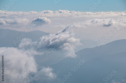 View over the clouds in the sky with mountains in the background