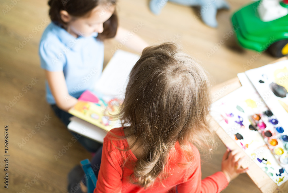 children engaged in creative work. Children sit at the table and draw watercolor. girl reading a book